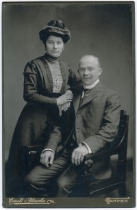 Mann in Stuhl und Frau daneben. 1910